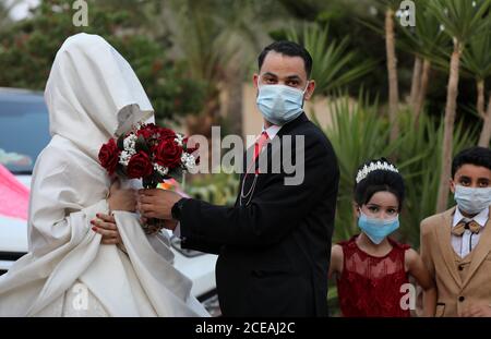 Khan Younis. 31st Aug, 2020. A Palestinian groom and his bride wearing face masks are seen at their wedding ceremony in the southern Gaza Strip city of Khan Younis, on Aug. 31, 2020. Palestine recorded the highest daily rise of COVID-19 cases on Monday after the outbreak of the deadly pandemic in the Palestinian territories in March. The health ministry recorded in the last 24 hours seven deaths and 875 new COVID-19 cases in the West Bank, East Jerusalem, and the Gaza Strip. Credit: Yasser Qudih/Xinhua/Alamy Live News Stock Photo