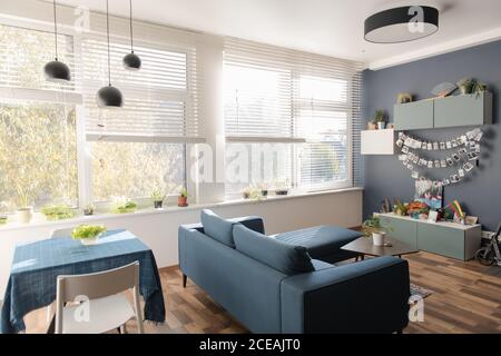 Comfortable sofa standing near furniture in stylish room of modern apartment on sunny day Stock Photo