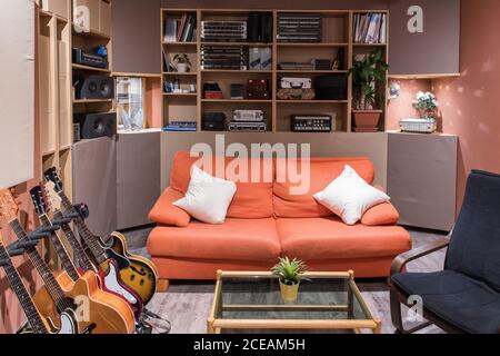 Set of various guitars standing near comfortable couch in stylish room in recording studio Stock Photo