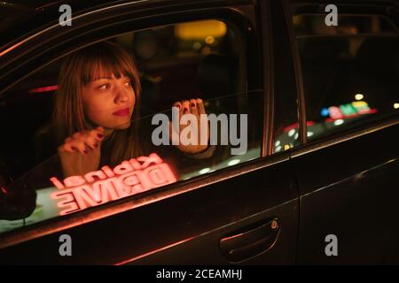 Young Woman in car looking away and reflection of Kibiniai drive inscription Stock Photo