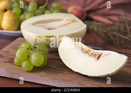Still life of fruit where you can see a slice of melon of the Matisse type next to some green grapes on a wooden table Stock Photo