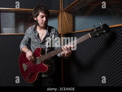 Handsome man playing electric guitar while rehearsing in modern recording studio. Stock Photo