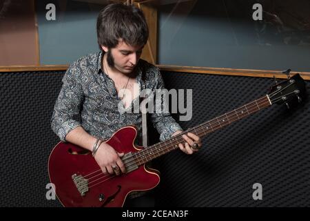 Handsome man playing electric guitar while rehearsing in modern recording studio. Stock Photo