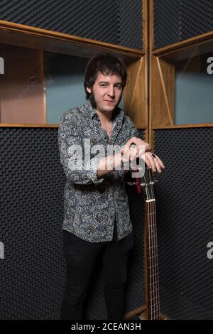 Handsome man playing electric guitar while rehearsing in modern recording studio. Stock Photo