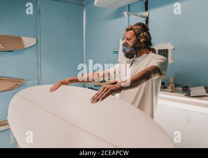 man holding surf board on stand in workshop Stock Photo