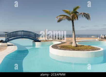 Small bridge and palm at blue pool in the hotel Stock Photo