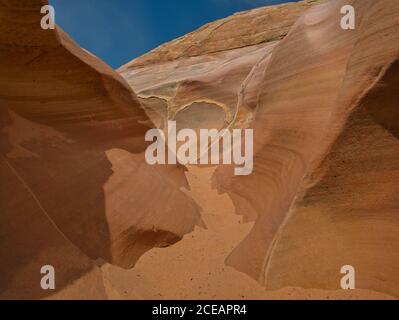 Fine sand in a small gorge with colorful striped rocks Stock Photo
