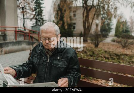 Elderly man reading newspaper in park Stock Photo