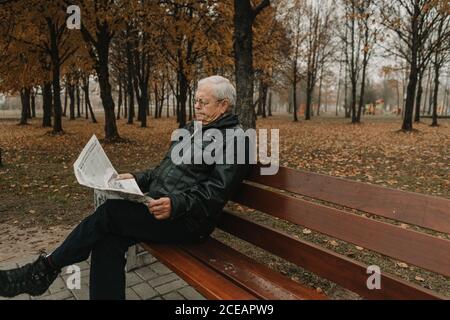 Elderly man reading newspaper in park Stock Photo