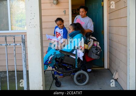 Sacramento, California, USA. 10th Feb, 2019. Felicia Clark pushes daughter Felicia Brent-Velasquez's wheelchair to catch the bus to school Feb. 10, 2020 as her son David shows his homework to his sister. 'We moved her here and been trying to figure out her new way of life. What that means is getting her back into school. All of my children have to go to school, education is key. I want her to do whatever she can with her brain. She's got full brain function. I don't want her to waste it,'' she said. Her daughter died in June from after suffering a stroke. (Credit Image: © Renée C. Stock Photo