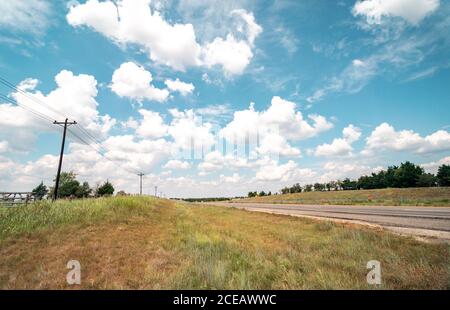 Low angle View of Empty Highway Passing Through Texas Fields with Utility Post along the side Stock Photo