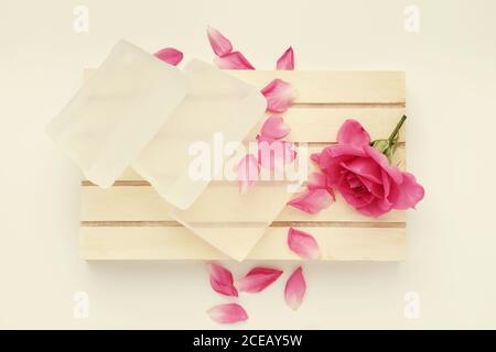 Soap bar and rose flower. Base for making soap and pink rose bud on wooden pallet. Top view. Stock Photo