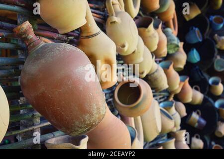 Rustic vintage clay jugs, pots and mugs hanging on the wall. Stock Photo