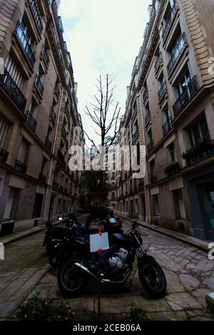 Different motorcycles parked on narrow street in Paris, France. Stock Photo