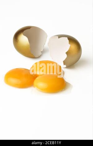 Broken golden egg and three yolks Stock Photo