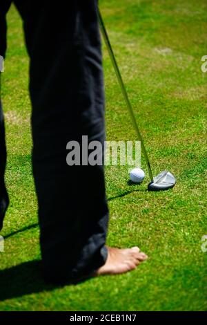 Crop back view of man in black trousers playing golf on green lawn at daylight Stock Photo