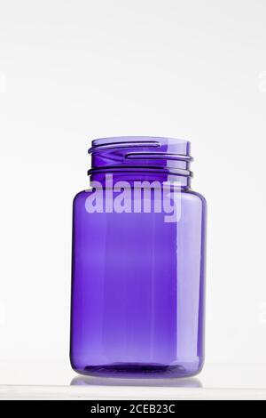 Plastic purple opened jar standing on shiny surface isolated on white background