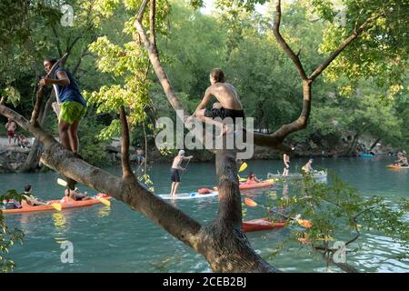 Young people eager to get outdoors during the coronavirus pandemic ignore social distancing guidelines to have fun in the cool waters of Barton Creek south of downtown Austin.These teenage boys are using a popular rope swing on a tree trunk overhanging the creek. ©Bob Daemmrich Stock Photo