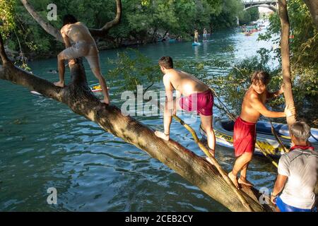 Young people eager to get outdoors during the coronavirus pandemic ignore social distancing guidelines to have fun in the cool waters of Barton Creek south of downtown Austin.These teenage boys are using a popular rope swing on a tree trunk overhanging the creek. ©Bob Daemmrich Stock Photo
