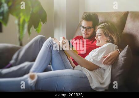Cheerful dreamy man and Woman lying on couch and reading brochure Stock Photo