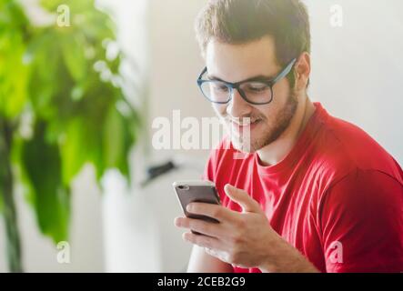 Young handsome bearded man in glasses on the smartphone at home Stock Photo