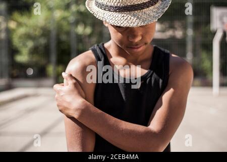 Afro young boy poses with straw hat on the basketball court of his 