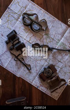 planning a trip on a map with vintage motorcycle glasses, old photo camera, prismatic and compass Stock Photo