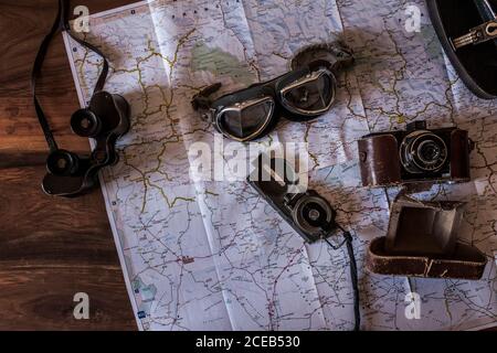 planning a trip on a map with vintage motorcycle glasses, old photo camera, prismatic and compass Stock Photo