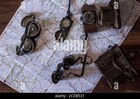 planning a trip on a map with vintage motorcycle glasses, old photo camera, prismatic and compass Stock Photo