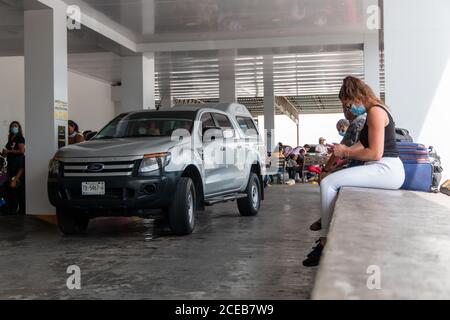 Cancun. Quintanaroo, Mexico. 08.17.2020 Real woman wearing a protective mask while waiting for a rental car to be delivered to her. New normal Stock Photo