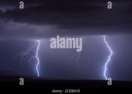 Lightning bolts strike in the night sky from a thunderstorm near ...