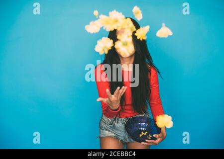 Young Woman standing in studio and throwing flowers Stock Photo