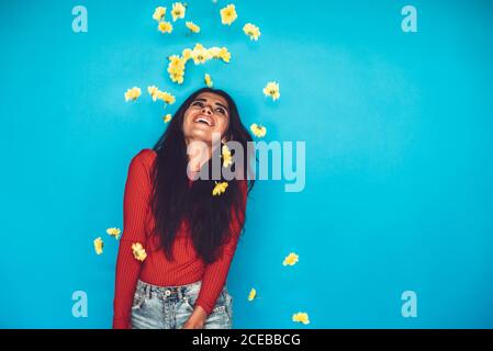 Young Woman standing in studio and throwing flowers Stock Photo