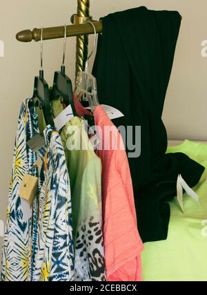 New clothes on small rack with paper price tags. Women's apparel on hangers ready for display. Tags have been erased and cut in different sizes/shapes. Stock Photo
