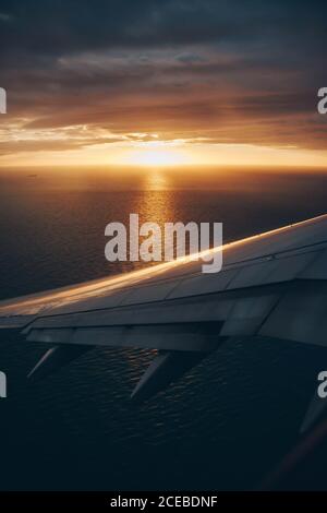 View through window of airplane wing above clouds and sky with sunshine Stock Photo