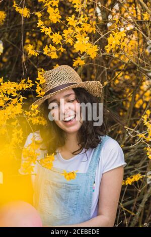 Happy laughing Woman standing with eyes closed in yellow blooming tree Stock Photo