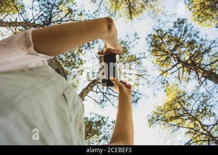 Excited young Woman standing in forest and taking photo with retro camera Stock Photo