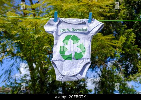 Recycle clothes icon on Babygro drying outside on washing line with 100% Recycled text, sustainable fashion concept illustration reuse, recycle clothe Stock Photo
