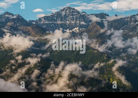 Wonderful view of top of high hills between clouds and beautiful blue sky Stock Photo