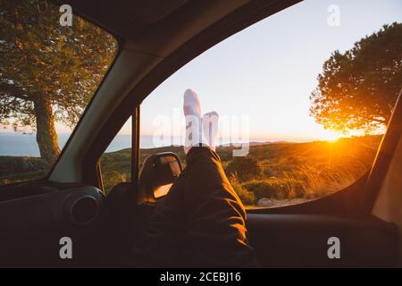 Crop legs in car during sunset Stock Photo