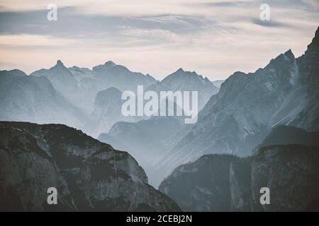 Thick clouds floating on sky over peaks of majestic mountain ridge in Dolomites, Italy Stock Photo