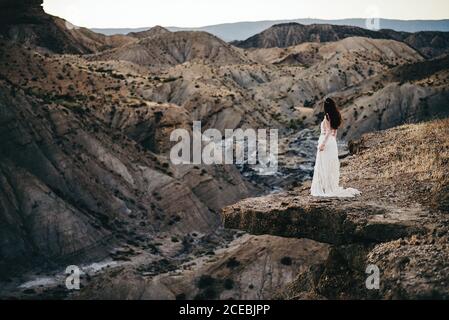Side view of young Woman wearing dress and looking away in the mountains. Stock Photo