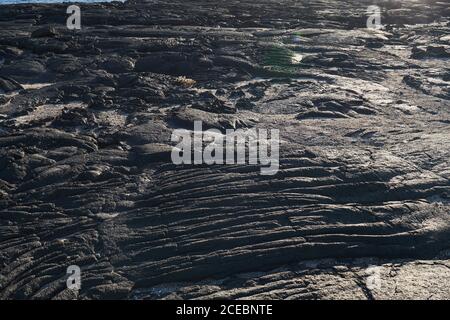 Closeup texture of dark rough rock in sunlight Stock Photo