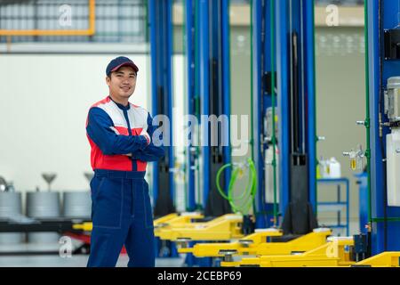 Asian man auto mechanic in auto repair service center black ground is a car lift. Stock Photo