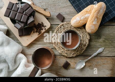 Top view of a hot chocolate cup, a cooper pot with hot chocolate and a cutting board with chocolate chunks Stock Photo
