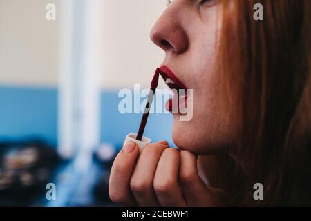Attractive red haired lady rouging lips Stock Photo