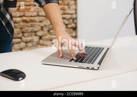 man typing on laptop at table near computer mouse Stock Photo