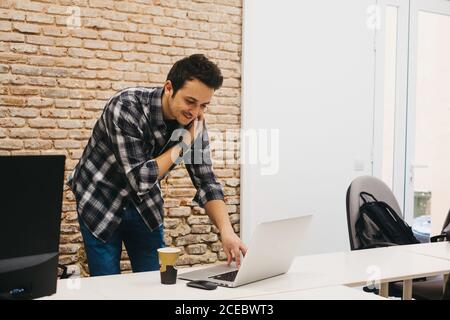Young man with cup talking on smartphone Stock Photo