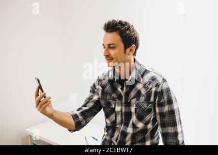 Smiling young man taking selfie on smartphone Stock Photo