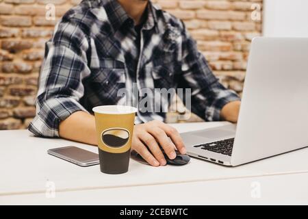 Young man using laptop at table with cup and smartphone Stock Photo